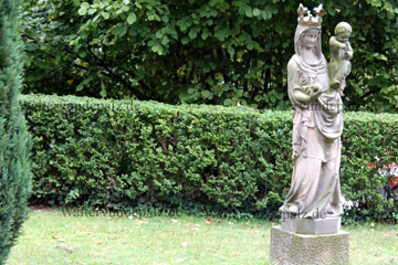 Mutter Gottes Statue mit ihrem Kind auf dem Arm aus Stein gehauen vor einer evangelischen Kirche in Rheinland-Pfalz.